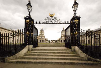 The picture shows, through eleborate black and gold wrought iron gates, the magnificent historic buildings of the Old Naval College at Greenwich on either side of the Queen's House, which is further away. In the background is the hill of Greenwich Park with the Royal Observatory high up on the right.